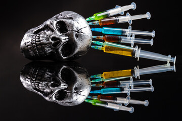 Metallic humans skull with colorful stucked syringes on black background. Reflective mirror...