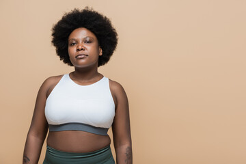 confident african american plus size woman in crop top isolated on beige.
