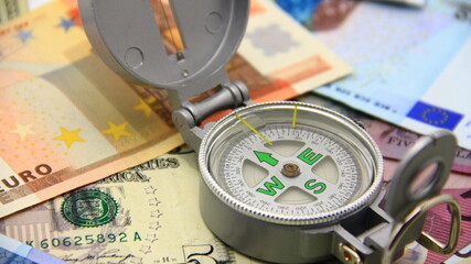 Compass on paper Euro and Dollar money. Crisis, direction, definition, concept.