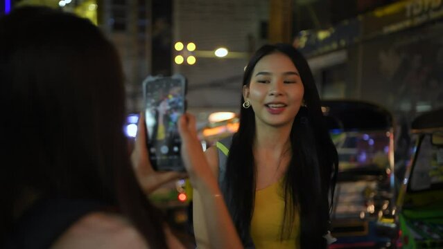 Travel concept of 4k Resolution. A beautiful girl is taking pictures on the pedestrian street at night.