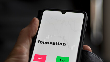 An investor's analyzing the innovation etf fund on screen. A phone shows the ETF's prices innovative to invest
