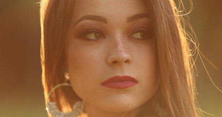 Pensive young woman during dreamlike golden hour sunset time. Thoughtful contemplative pretty girl...