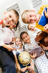 Low angle shot of female teacher huddling with elementary students pupils in school indoor. Back to school concept. Vertical shot.