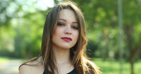 Naklejka premium Millennial pretty head headshot portrait posing in outdoor park smiling to camera