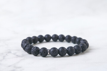 Wrist bracelet made of volcanic lava on a light background, space for text