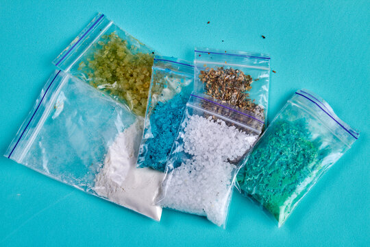 Plastic packets with various different colorful drugs. Isolated on blue background.