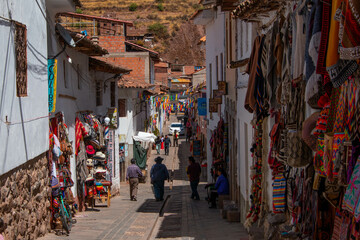 Typical street in the town of Pisac with its colorful stores, mountain view and a beautiful blue sky with clouds, in Peru.