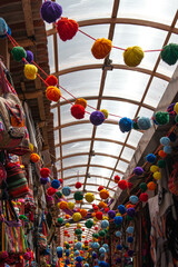 Inside the new handicraft market of Pisac, decorated with colorful pompoms and various typical products, in Peru.  - obrazy, fototapety, plakaty