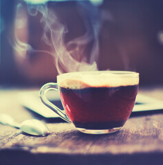 cup of hot coffee with book over window