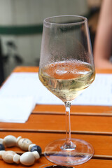 white wine glass with ice and human hand closeup photo on outdoor cafe background