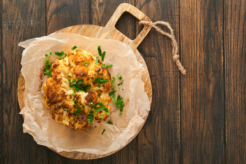 Baked cauliflower. Oven or whole baked cauliflower spices and herbs server on wooden rustic board...
