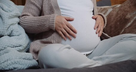 Pregnant woman sitting crossed legged on the sofa - Powered by Adobe