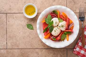 Caprese salad. Italian caprese salad with sliced tomatoes, mozzarella cheese, basil, olive oil in white plate over old brick tiles brown background. Delicious Italian food. Top view. Rustic style.