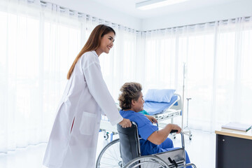 Obraz premium Young attractive Asian doctor is helping an old patient in a wheelchair walking, hospital and healthcare concept.