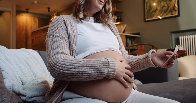 Pregnant female rubbing her belly while looking at her sonogram picture