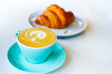 a green color cup of late coffee with flower shape design 