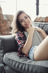 Obraz premium Comfortable and Cozy: Blonde Girl Posing in Various Relaxing Positions at Home, Reading and Working on Laptop