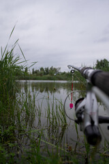 A fishing rod equipped with a mechanical signal on the shore of the lake, waiting for a fish bite
