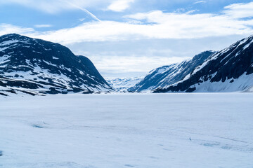 Landscape of a frozen lake with mountains in the background and lots of snow in Norway.