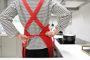 Back view of woman preparing food while tying her apron in the kitchen - Powered by Adobe