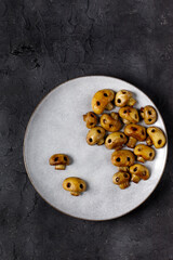 Round plate with mushrooms in the form of skulls and fork on white table. Edible Halloween Concept