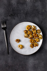 Round plate with mushrooms in the form of skulls and fork on white table. Edible Halloween Concept