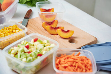 Fresh cut vegetables for freezing on table in kitchen. Slice of peaches and knife on cut board.
