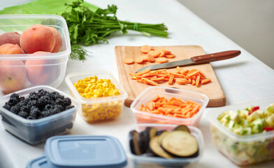 Fresh cut vegetables for freezing on table in kitchen. Slice of carrot and knife on cut board.