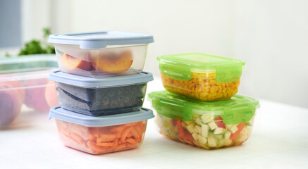 Plastic containers with raw cut vegetables for freezing on kitchen table. Storage for winter storage in trays