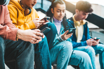 Millennial friends watching smart mobile phone device outside - Young people using cellphones playing on social media platforms - Technology addiction concept