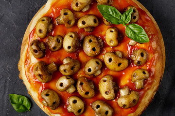 Homemade pizza with tomato sauce and mushrooms in the form of skulls. Concept for Halloween celebrations