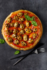 Homemade pizza with tomato sauce and mushrooms in the form of skulls. Concept for Halloween celebrations