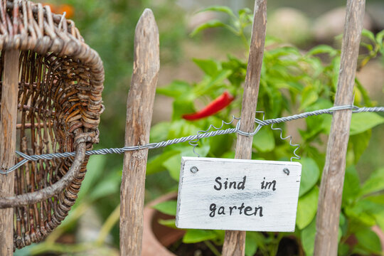 Gartenzaun mit Schild, Korb und Peperoni