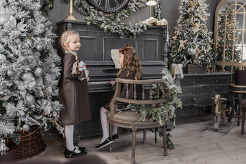 Two cute 5-6-year-old girls on a piano background in Christmas and New Year decorations. Retro style