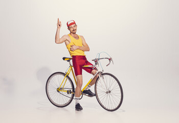Portrait of young man in colorful clothes, uniform riding bike isolated over grey background. Pizza...