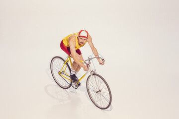 Portrait of young man in colorful clothes, uniform riding bike isolated over grey background. Racer. Top view