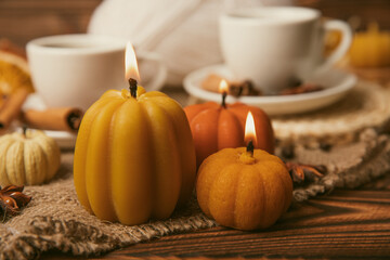 Candles in the form of pumpkins with fragrant coffee on a background of spicy spices of star anise and cinnamon on a brown wooden background.Cozy home decor.Halloween concept.Happy Thanksgiving.