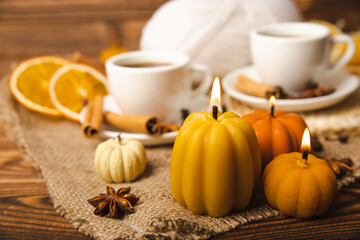 Candles in the form of pumpkins with fragrant coffee on a background of spicy spices of star anise and cinnamon on a brown wooden background.Cozy home decor.Halloween concept.Happy Thanksgiving.