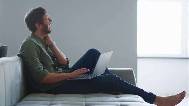 neck ache after long laptop using, freelancer man is surfing internet and working at home