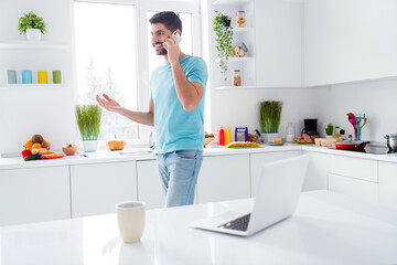 Portrait of cheerful satisfied young man hold communicate telephone bright kitchen room indoors
