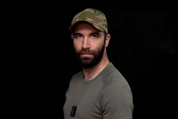 Portrait of a 30-36-year-old man in a military cap and T-shirt with army medallions on his chest,...