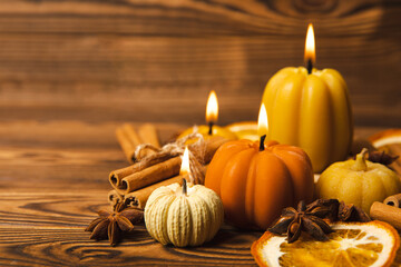 Autumn composition.Pumpkin candles,spicy star anise spices and cinnamon on a brown wooden background.Cozy home decor.Halloween concept.Happy Thanksgiving.Flat lay.Copy space.