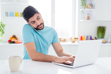 Portrait of serious handsome guy speak communicate telephone typing message netbook house morning indoors