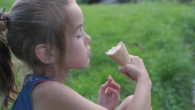 teen cute caucasian girl eating ice cream, Child enjoying ice cream, holding an ice cream cone and taking a bite of dessert