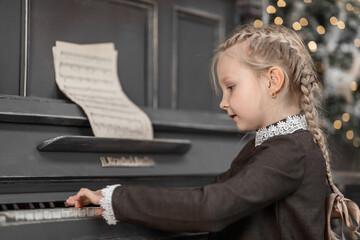 Portrait of a 5-6-year-old girl playing the piano in the New Year, the concept of a holiday in retro style