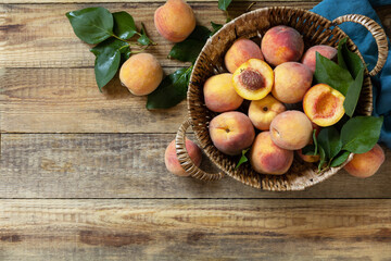 Naklejka na ściany i meble Organic fruits. Fall harvest background. Farmer's market. Basket of ripe peaches on a rustic wooden table. View from above. Copy space.