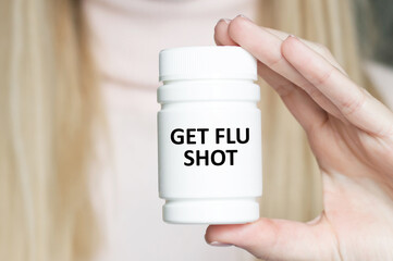 Get Your Flu Shot text on the label of a white jar with medicine in the hand of a girl doctor, medical concept