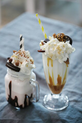 two ice cream sundaes sitting next to each other, milkshake, drink milkshakes together, milk and mocha style, maple syrup & hot fudge, ice coffee, regular sized