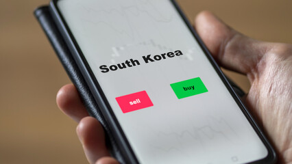 Un investisseur analyse le fonds ETF sud-coréen à l'écran. Un téléphone montre les prix de l'ETF sud-coréen à investir, texte en anglais.