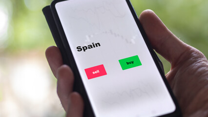 An investor's analyzing the Spain etf fund on screen. A phone shows the ETF's prices Spainish to invest
